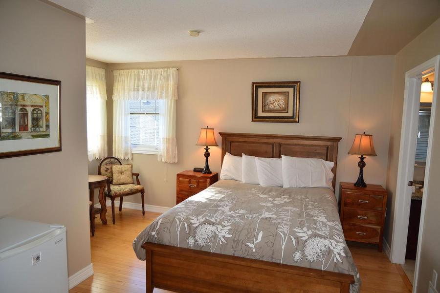 1 dormitorio con cama, escritorio y silla en Arnica Bed & Breakfast, en Niagara on the Lake