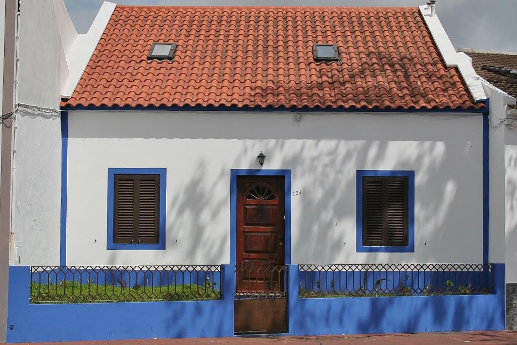 una casa blanca con techo rojo y puerta en Casa Azul Natura, en Ponta Delgada