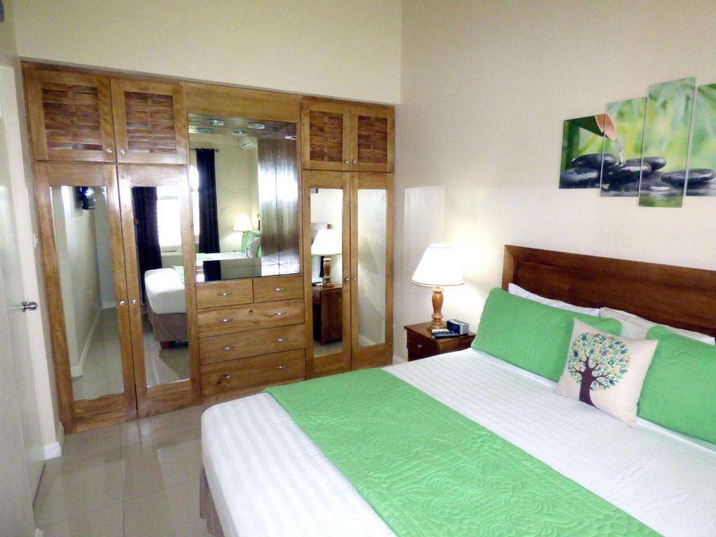 Un dormitorio con una cama verde y blanca y un baño. en Beach One Bedroom Suite A29, en Ocho Ríos