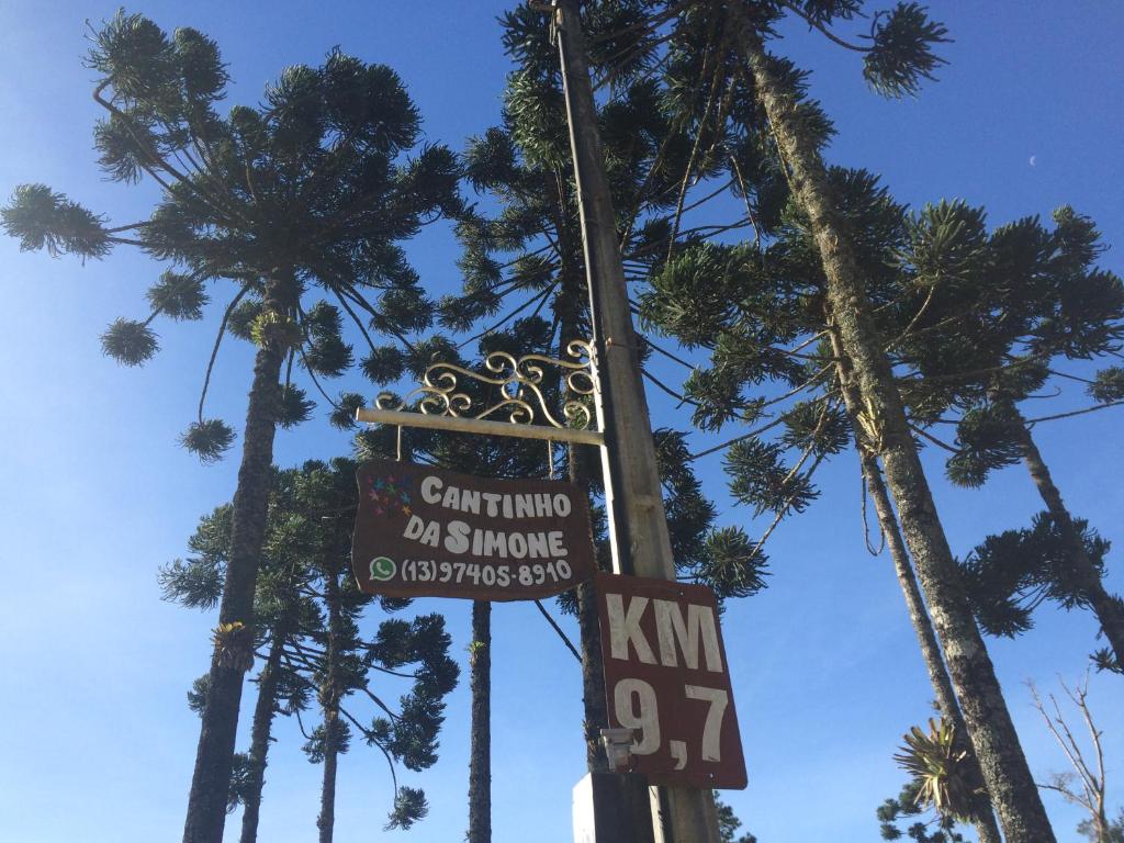 a street sign on a pole with palm trees at Cantinho da Simone in Campos do Jordão