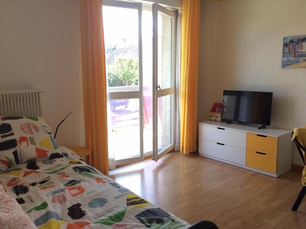 a bedroom with a bed and a tv and a window at Residence les Goelands in Ouistreham