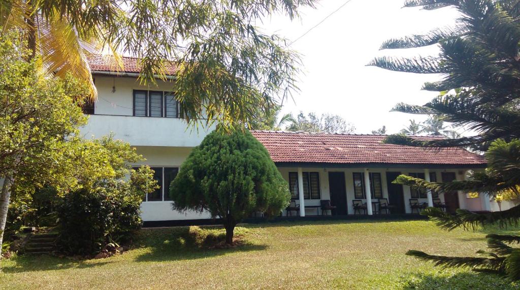 a house with a tree in front of it at 4 Seasons Guesthouse in Hikkaduwa