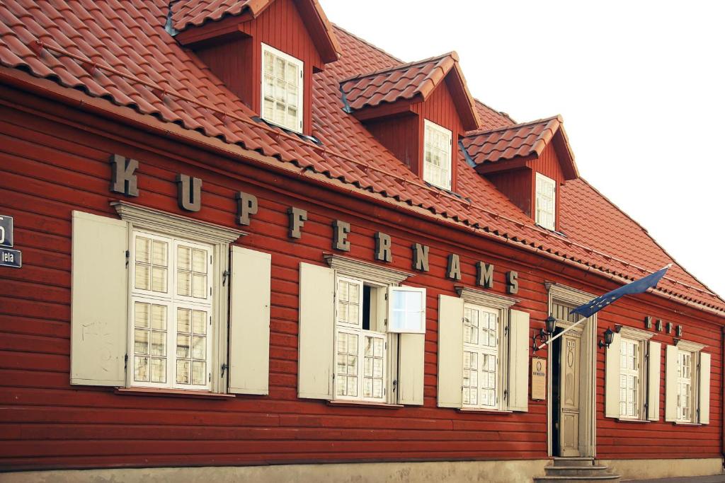 un edificio rojo con techo rojo y ventanas blancas en Kupfernams, en Ventspils
