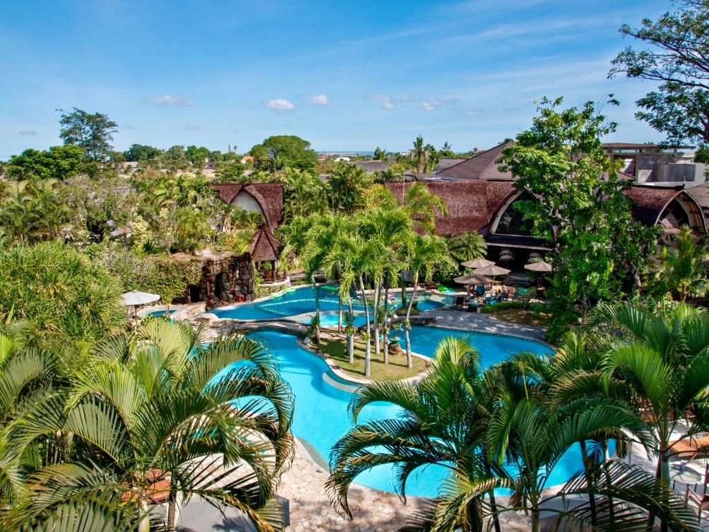 an aerial view of a resort pool with palm trees at Hotel Vila Lumbung in Seminyak