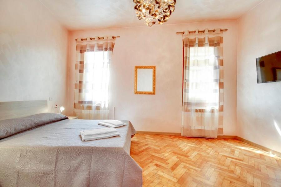 a bedroom with a bed and two windows and a chandelier at Locanda Delle Acque in Venice