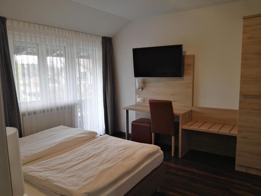 a hotel room with a bed and a desk and a television at Hotel Gasthof Momm in Brunnthal