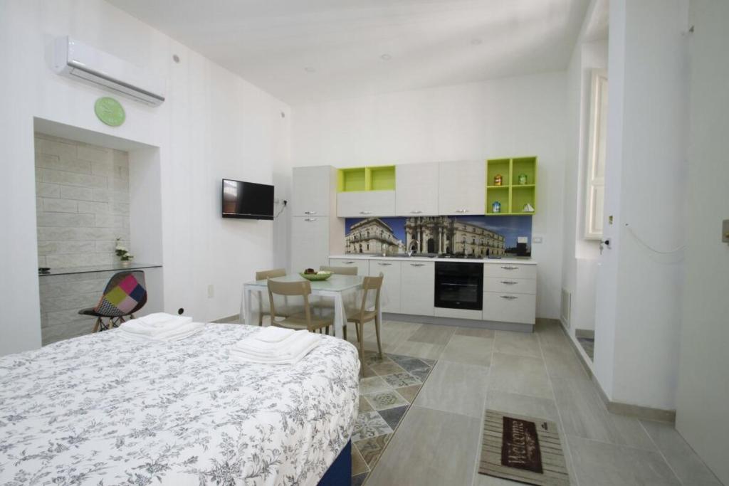 Habitación blanca con cama y cocina en Casa Vacanze Ortigia, en Siracusa
