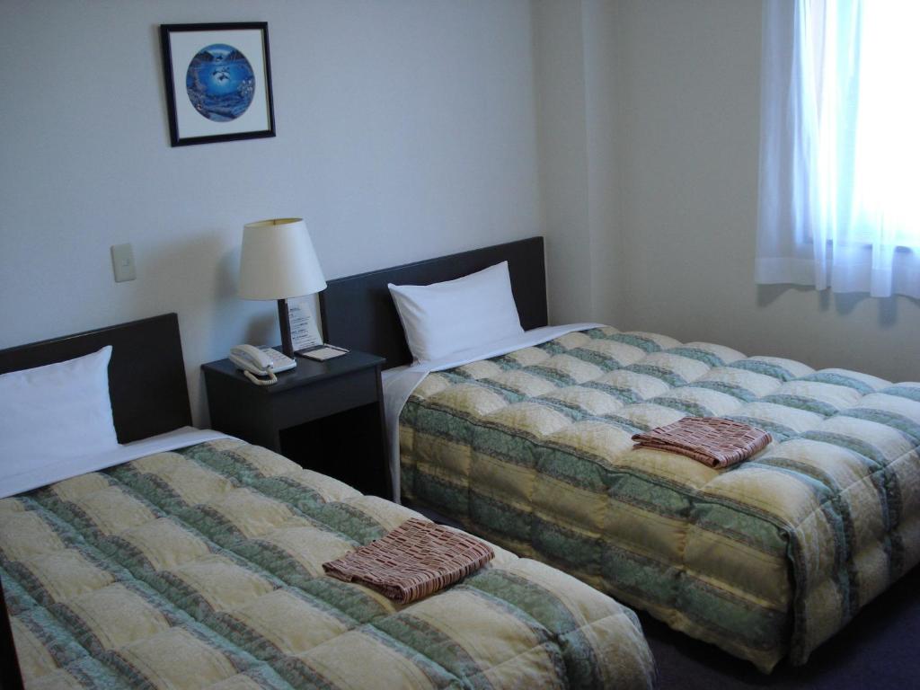 una habitación de hotel con 2 camas y una lámpara en Hotel Route-Inn Itoigawa, en Itoigawa