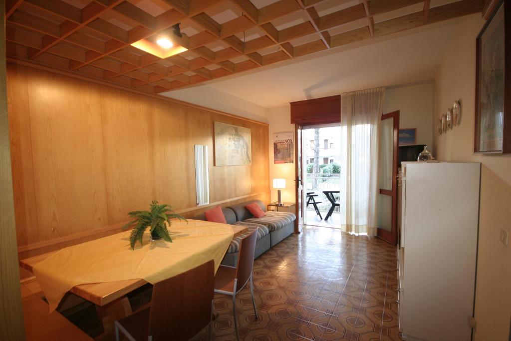 a living room with a table and a refrigerator at Michelangelo Apartment in Lignano Sabbiadoro