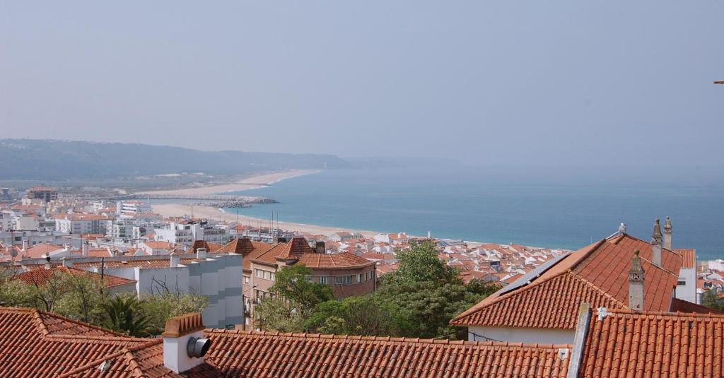Blick auf eine Stadt mit Häusern und das Meer in der Unterkunft Apartamentos Mare in Nazaré