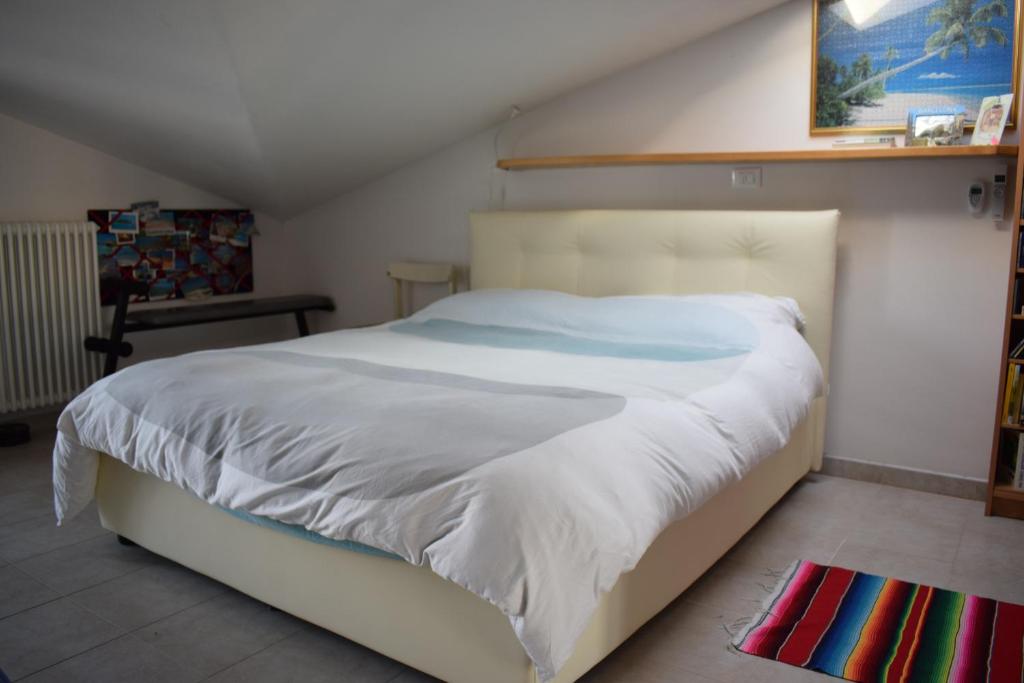 een slaapkamer met een groot bed met witte lakens bij Bilocale Attico Villamarina in Cesenatico