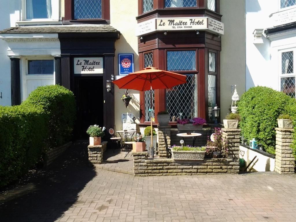 a table with an umbrella in front of a building at Le Maitre in Southport