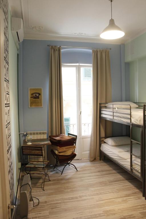 - une chambre avec des lits superposés et un bureau dans l'établissement Victoria House Hostel, à Gênes