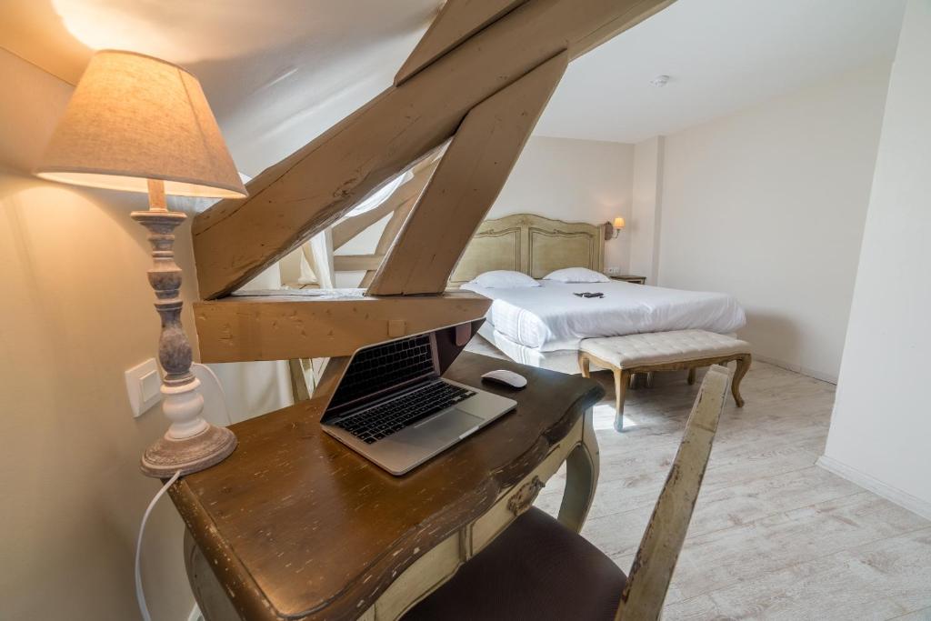 a bedroom with a desk with a laptop on it at The Originals Boutique, Hôtel Les Poèmes de Chartres in Chartres