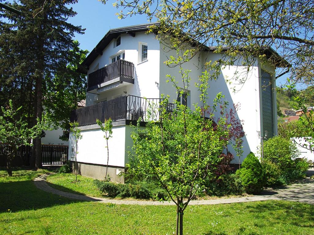 a white house with a balcony and a tree at Apartment Zupan in Maribor