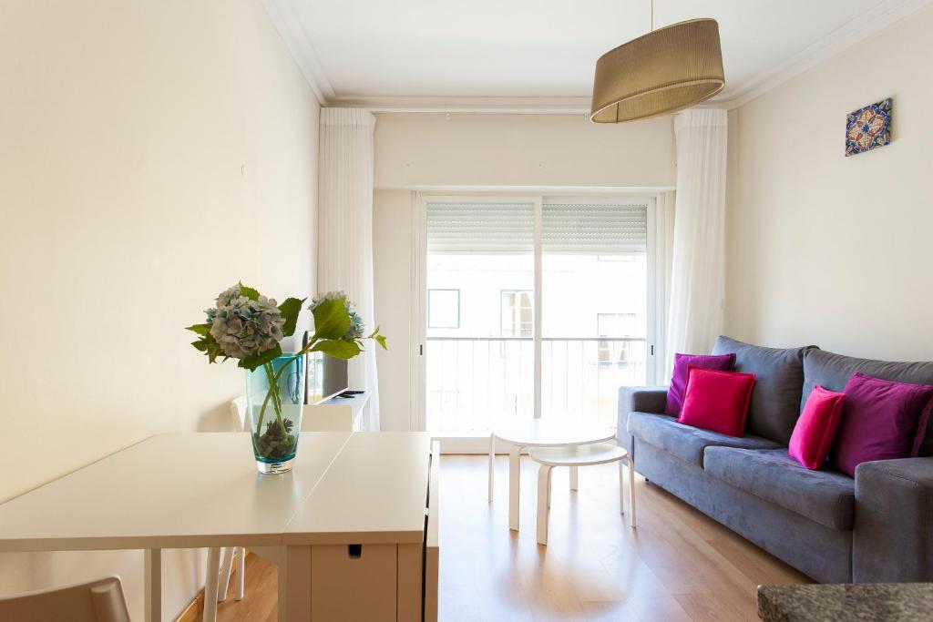 uma sala de estar com um sofá e uma mesa em JOIVY Bright 2BR Apt with River Views &balcony in Alfama, moments from Santa Apolonia train station em Lisboa