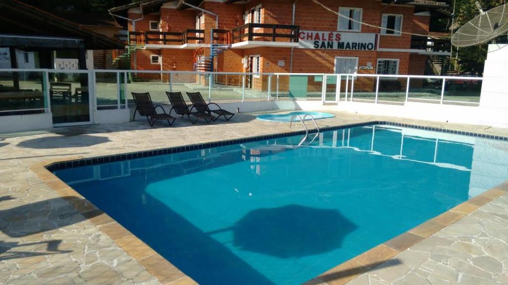 a large blue swimming pool in front of a building at Cond Apartamentos Chalés San Marino in Ubatuba