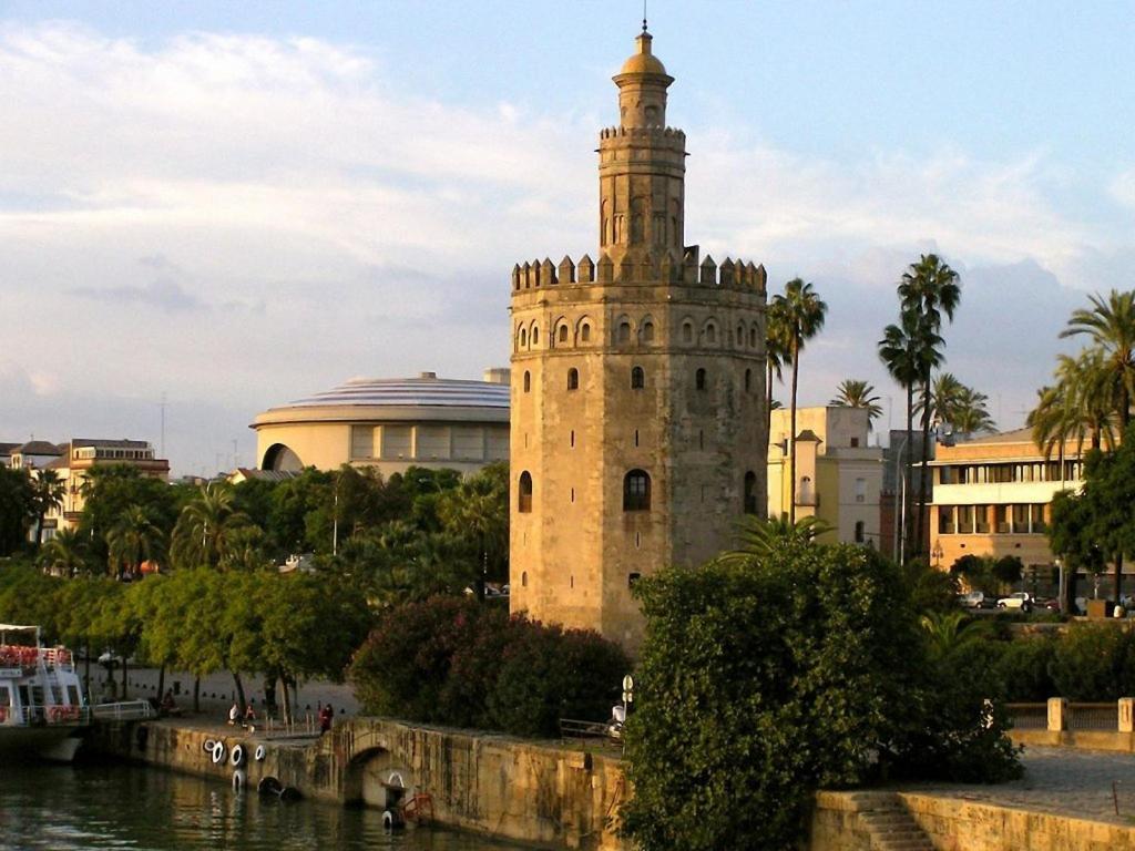 a tall building with a clock tower next to a river at Ático Feria in Seville