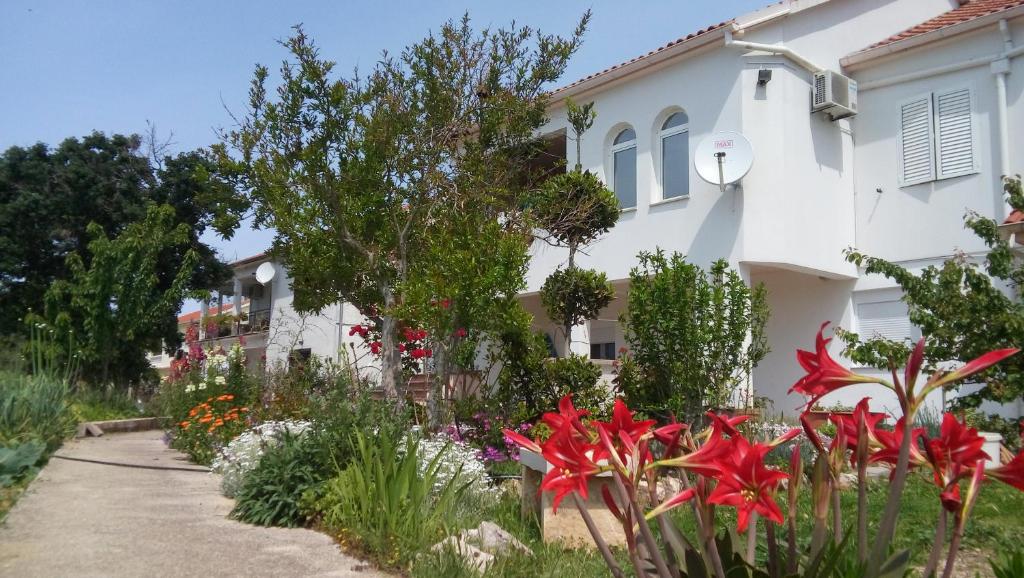 ogród przed białym domem z kwiatami w obiekcie Apartman La maison w mieście Zadar