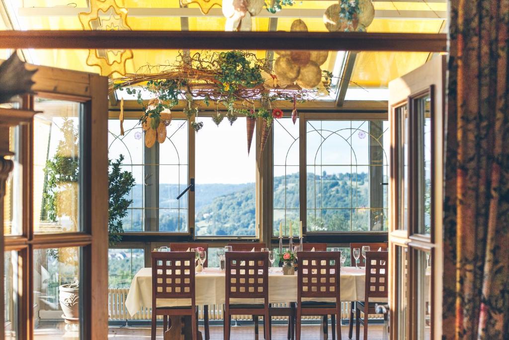 a dining room with a table and chairs and windows at Hotel Gasthof Schönblick in Neumarkt in der Oberpfalz