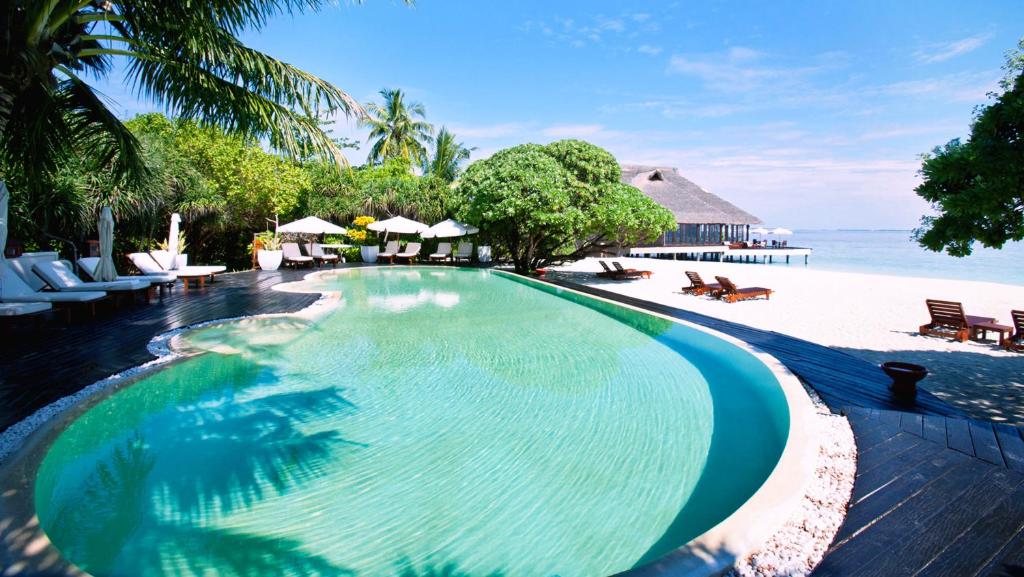 a large swimming pool next to a beach at Adaaran Prestige Water Villas - with Dine around Premium All inclusive - 24 hours in Raa Atoll