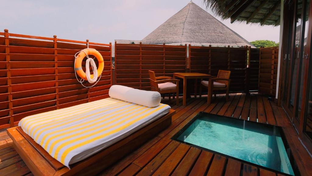 a bed and a table on a deck with a pool at Adaaran Prestige Water Villas - with Dine around Premium All inclusive - 24 hours in Raa Atoll