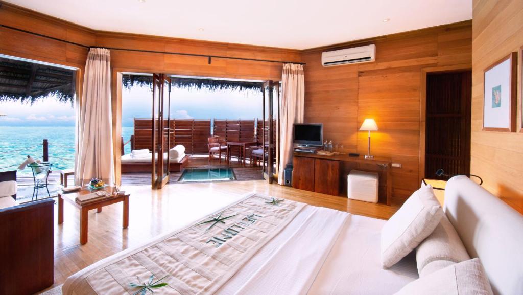 a living room with a couch and a television at Adaaran Prestige Water Villas - with Dine around Premium All inclusive - 24 hours in Raa Atoll