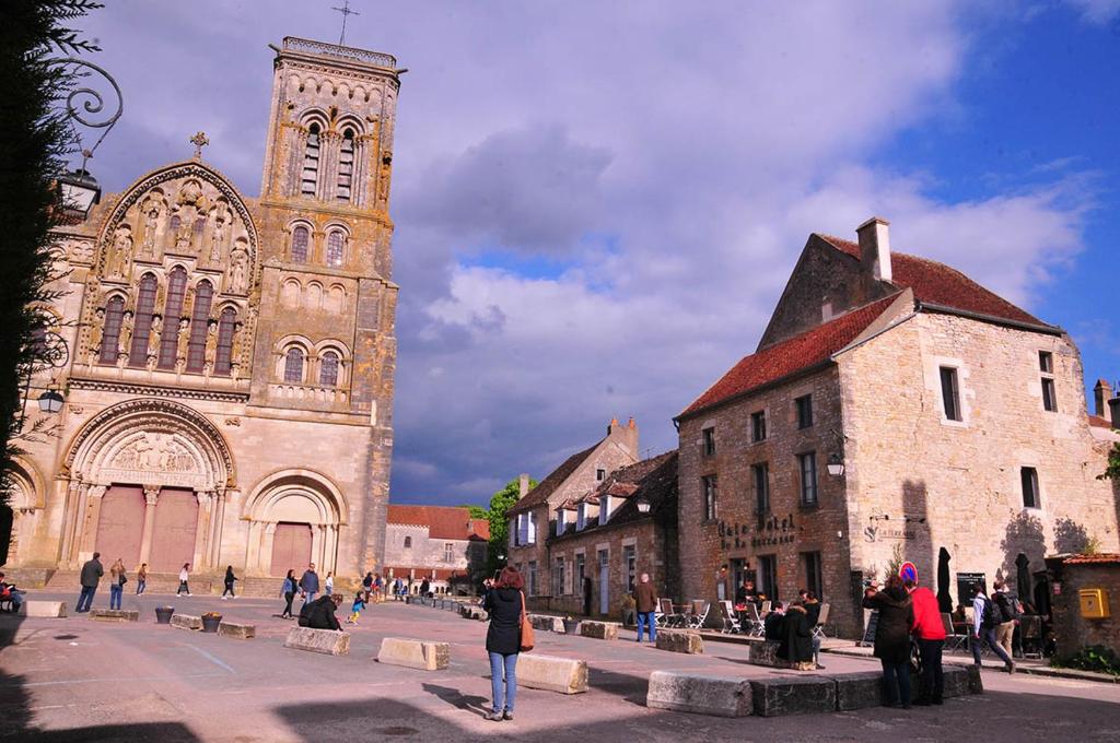 un grupo de personas caminando delante de una iglesia en SY-la terrasse en Vézelay