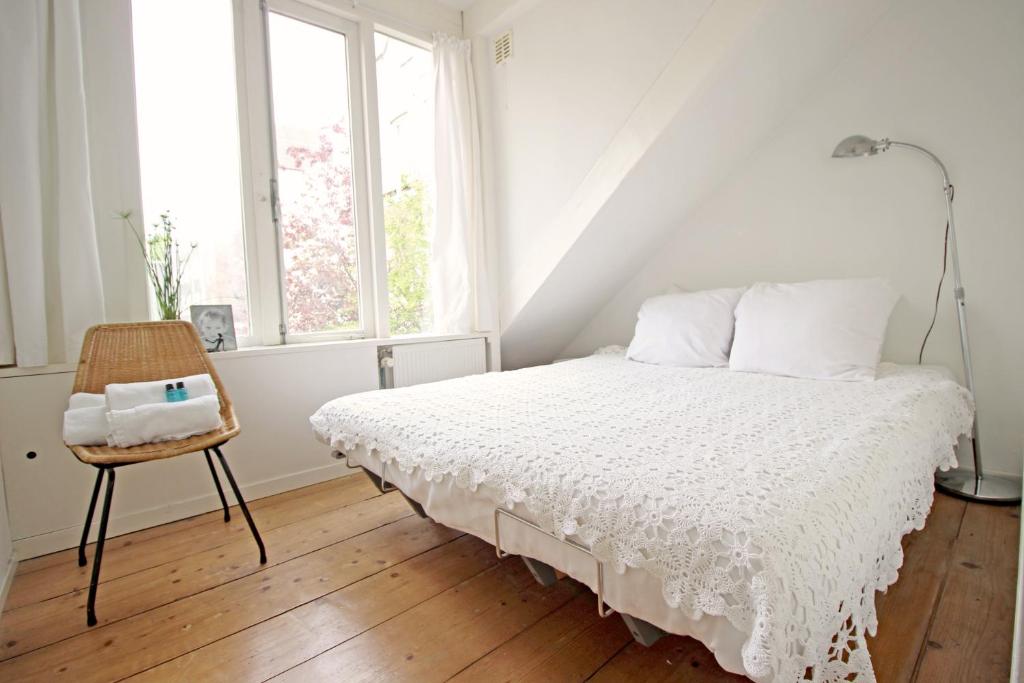 ein weißes Schlafzimmer mit einem Bett und einem Stuhl in der Unterkunft Beautiful 2 floor Vondelpark apartment. in Amsterdam