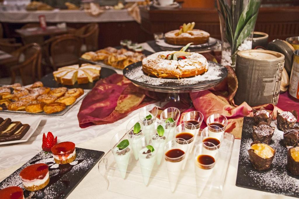 une table remplie de différents types de pâtisseries et de desserts dans l'établissement Hotel La Pace, à Pise