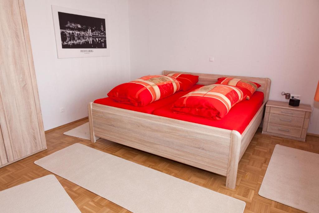 uma cama com lençóis vermelhos e almofadas vermelhas num quarto em Ferienwohnung Kurrer em Plankstadt