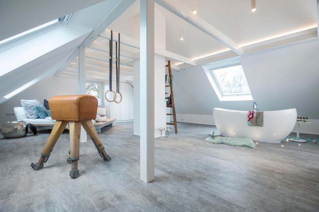 a attic room with a bath tub and a chair at Design-Studiowohnung Haegestrasse in Gütersloh