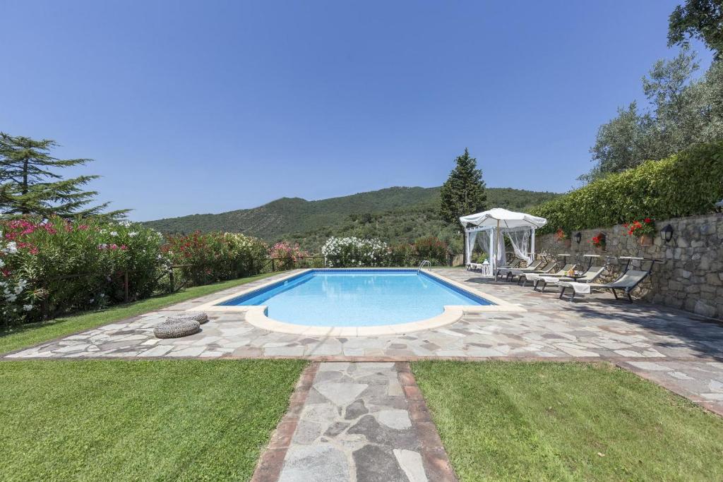 een zwembad in een tuin met een tafel en stoelen bij Villa ai Cedri in Cortona