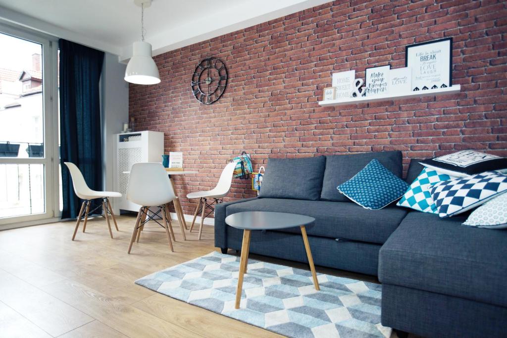 sala de estar con sofá azul y pared de ladrillo en Apartament Kowalska, en Gdansk