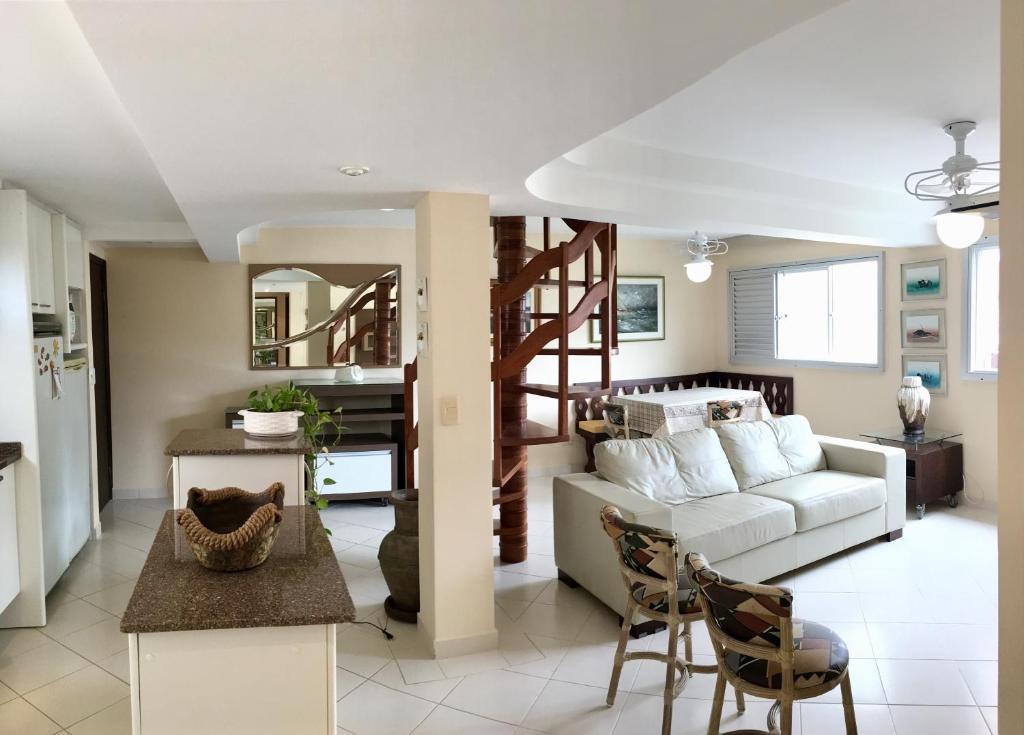 uma sala de estar com um sofá branco e escadas em Linda Cobertura Caiobá, amplo terraço com churrasqueira, e linda vista na Av Atlântica, Edificio Frente Mar em Caiobá
