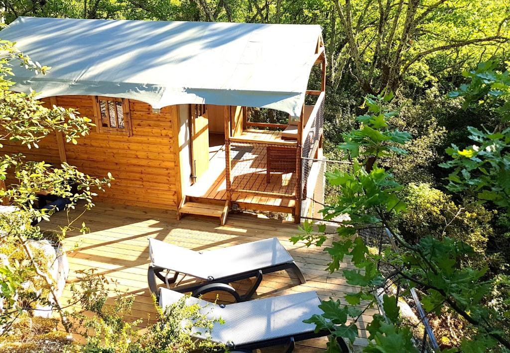 eine Holzterrasse mit einem Stuhl und einem Zelt in der Unterkunft Cabanes Lodges Le Servière in Balazuc