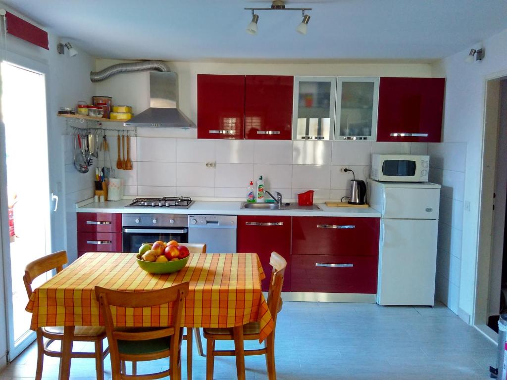 a kitchen with red cabinets and a table with a bowl of fruit at Apartman Nora in Hvar