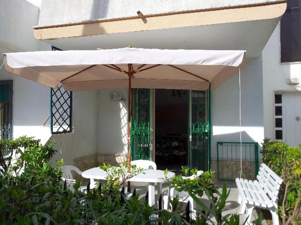 einen Tisch und Stühle unter einem Schirm vor einem Gebäude in der Unterkunft Villetta mare blu Baia Verde in Gallipoli