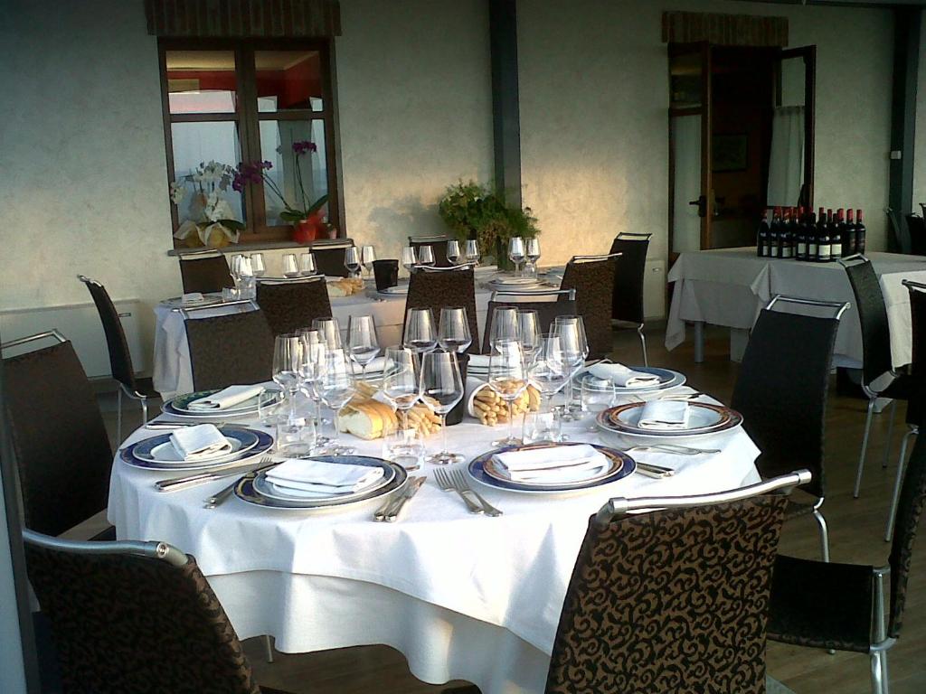 une table avec un chiffon de table blanc, des assiettes et de l'argenterie dans l'établissement La rosa dei vini, à Serralunga d'Alba