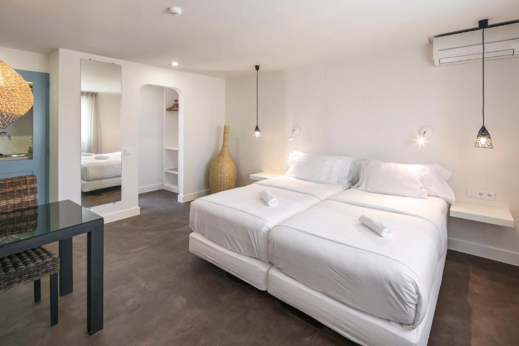 a white bedroom with a large bed and a table at Costa d'Oiro Ambiance Village in Lagos