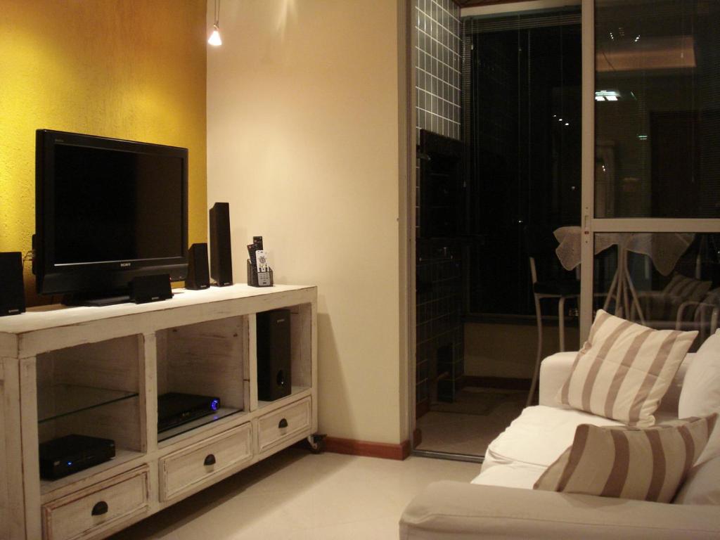 sala de estar con TV y sofá blanco en Apartamento Das Palmeiras, en Porto Alegre