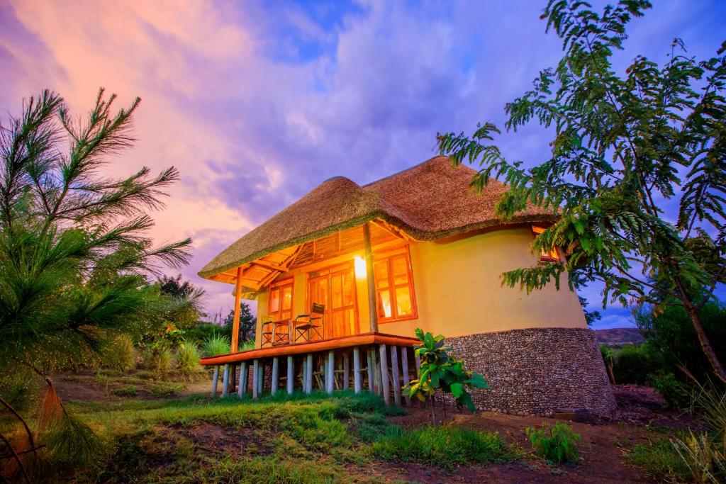 a small house with a thatched roof at Wild Tracks Overland Camp in Kasese