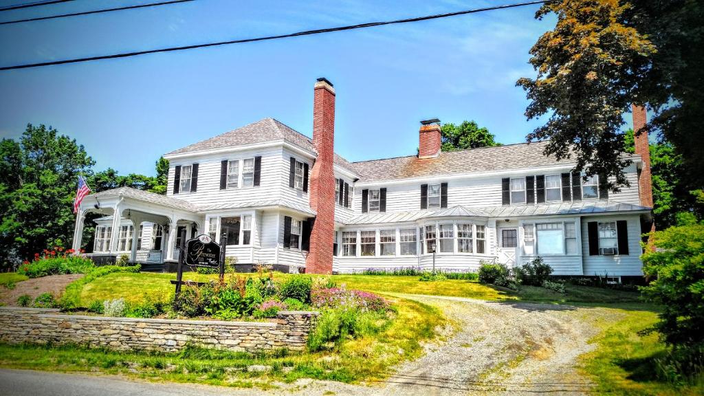 una casa blanca con dos chimeneas en The Brewster Inn, en Dexter