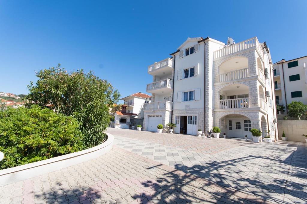 ein großes weißes Apartmenthaus mit einer Backsteineinfahrt in der Unterkunft Villa Snježana in Trogir
