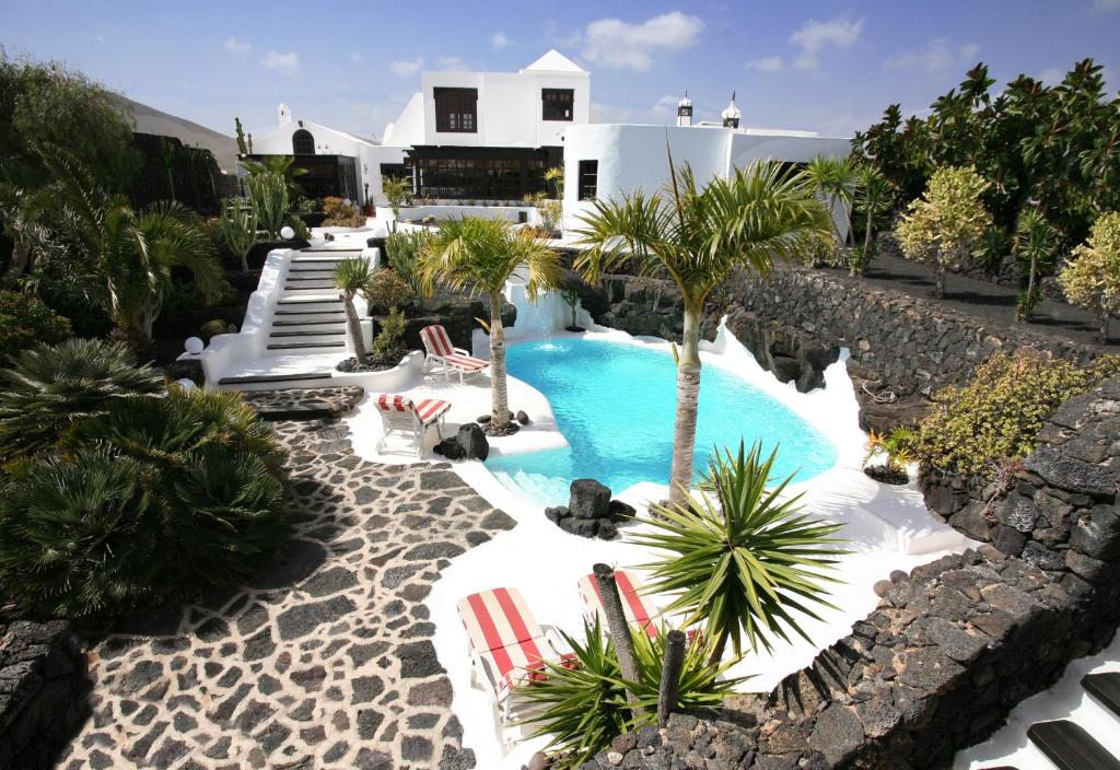 une piscine avec 2 chaises longues et une maison dans l'établissement Casa Teiga, à Tahiche