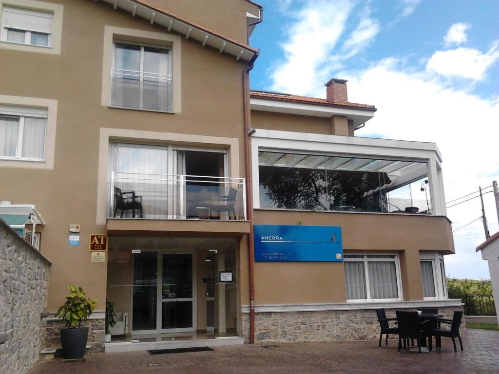 a large building with a balcony and a table at Apartamentos Áncora in Barro de Llanes