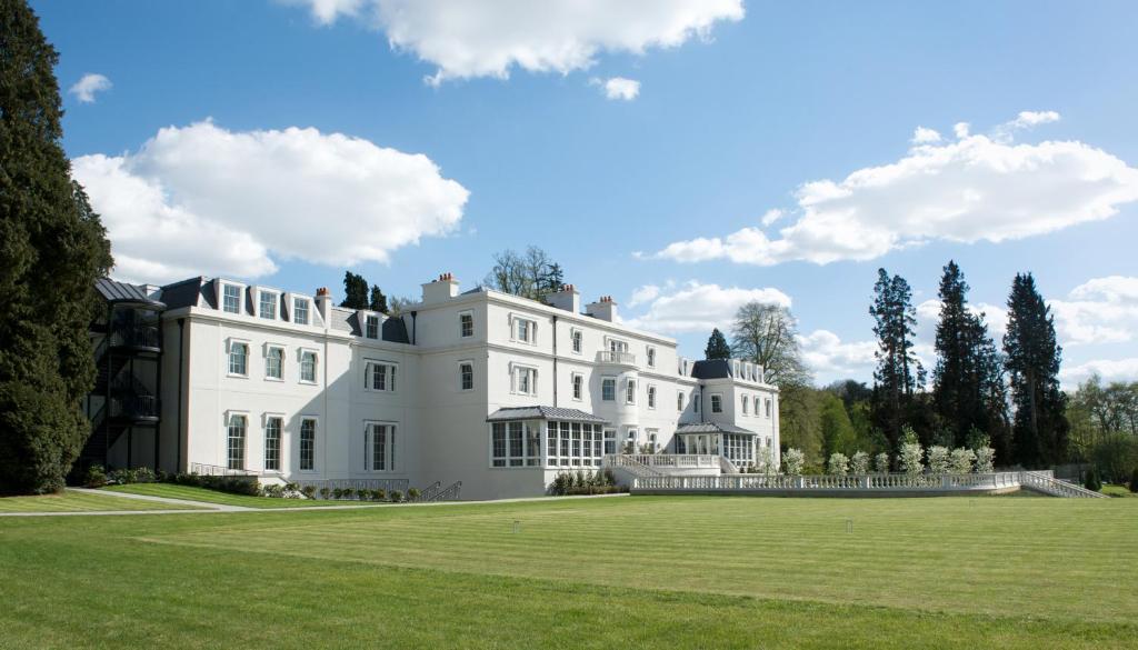 a large white house with a large grass field at Coworth Park - Dorchester Collection in Ascot