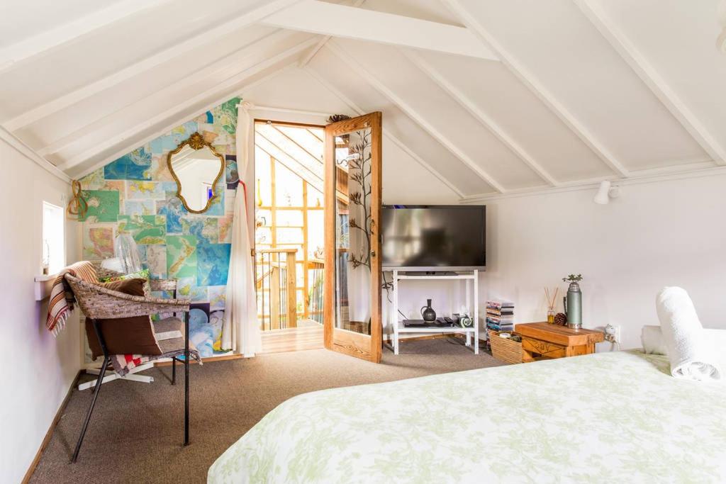 a bedroom with a bed and a tv in a room at Waiheke Island Guesthouse in Ostend