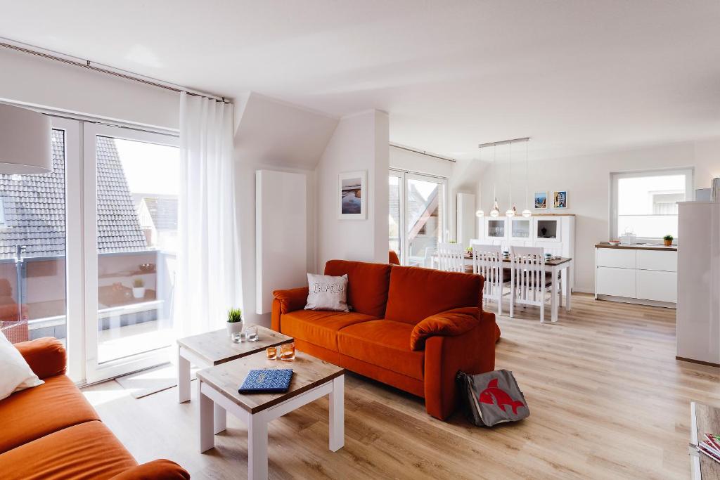 ein Wohnzimmer mit einem orangenen Sofa und einem Tisch in der Unterkunft Zuhause am Meer in Büsum