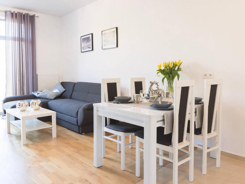 a living room with a white table and a blue couch at VacationClub - Diune Apartment 41 in Kołobrzeg